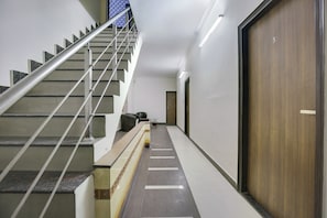 Un interior moderno con una escalera, un mostrador de recepción y una puerta de madera.