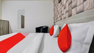 A hotel room with a bed, a wardrobe, a mirror, and a wall with a patterned design.