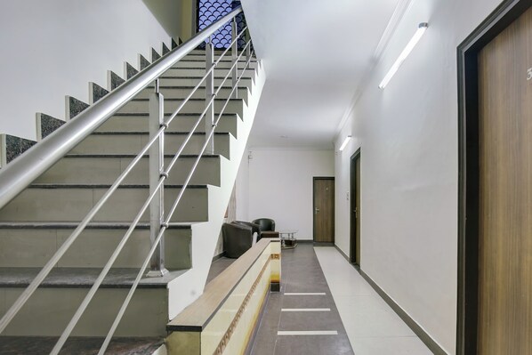 A modern staircase with metal railings and a handrail, leading to a door marked with the number 3.