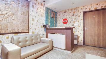 Ein Empfangsbereich mit einer Couch, einem Empfangstresen und einer Wand mit geometrischem Muster.