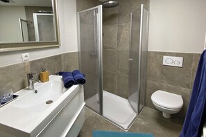 Une salle de bain moderne équipée d’une baignoire, d’un espace de douche et de toilettes.