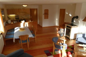 Ein gemütliches Wohnzimmer mit einer Couch, einem Esstisch mit Stühlen, einem farbenfrohen Teppich und einem Kamin.