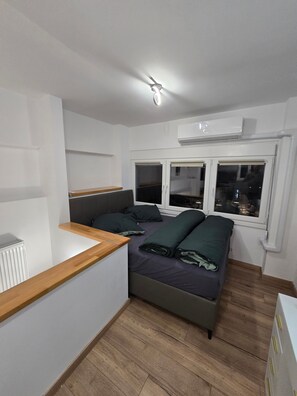 A small, modern room with a bed, a wooden desk, and a window. - Modern apartment in Thessaloniki (Θεσσαλονίκη)