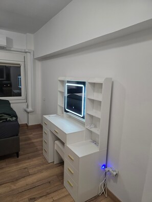 A bedroom with a white desk, a bed with a green blanket, and a window with blinds. - Modern apartment in Thessaloniki (Θεσσαλονίκη)