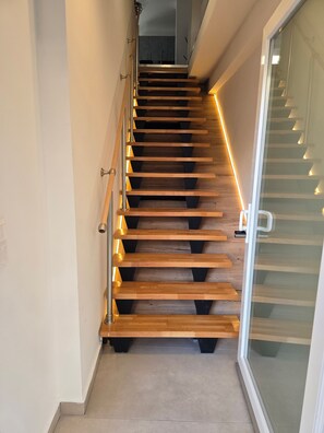 A wooden staircase with a handrail and glass doors at the top. - Modern apartment in Thessaloniki (Θεσσαλονίκη)