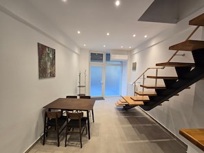 A modern interior with a dining area, staircase, and a door leading to a bright room. - Holiday Home 'Modern Apartment' with Wi-Fi and Air Conditioning (Θεσσαλονίκη)