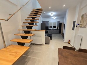A modern interior with a wooden staircase, a kitchen area, and a dining space. - Holiday Home 'Modern Apartment' with Wi-Fi and Air Conditioning (Θεσσαλονίκη)