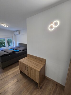 A modern bedroom with a bed, bedside table, and a wall-mounted light fixture. - Holiday Home 'Modern Apartment' with Wi-Fi and Air Conditioning (Θεσσαλονίκη)