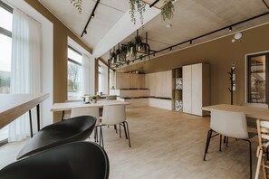 Eine moderne Küche mit Holzschränken, ein Essbereich mit Tisch und Stühlen und ein Blick durch das Fenster.
