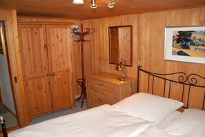 A wooden-paneled room with a bed, a dresser, a mirror, and a coat rack. - Country House Jäger Holiday Apartment No. 1 (Todtnauberg)