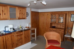 A kitchen with wooden cabinets, a coffee maker, and a sink. - Country House Jäger Holiday Apartment No. 1 (Todtnauberg)