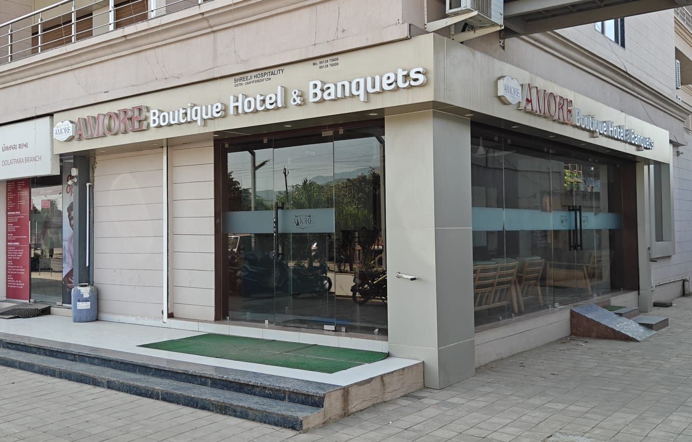A boutique hotel with a glass facade and a visible outdoor seating area.