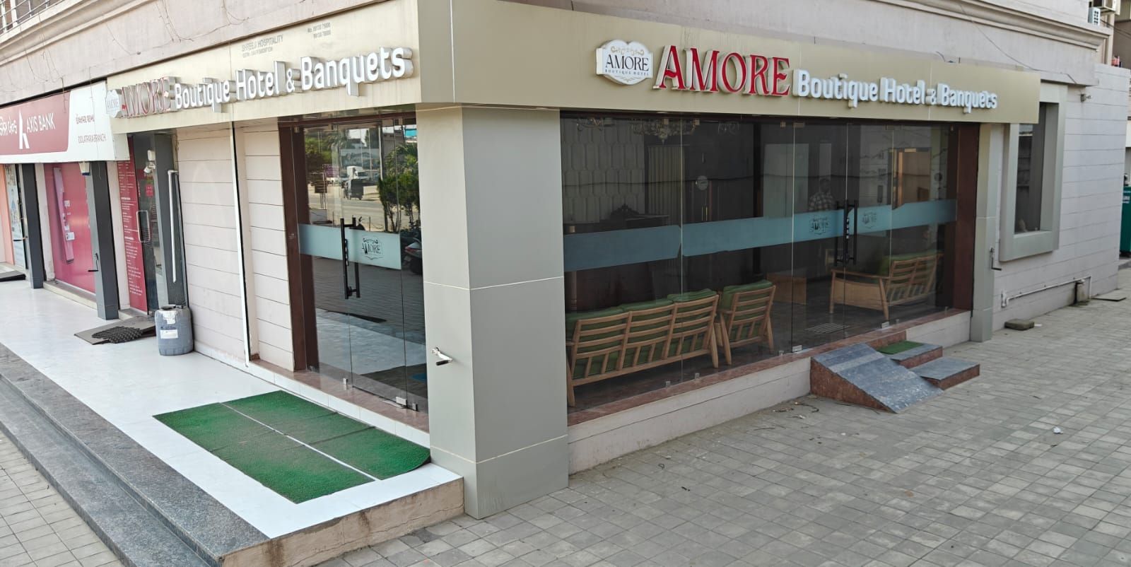 Un hotel boutique con fachada de vidrio, asientos exteriores y entrada visible.