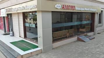 Un hotel boutique con fachada de vidrio, asientos exteriores y entrada visible.