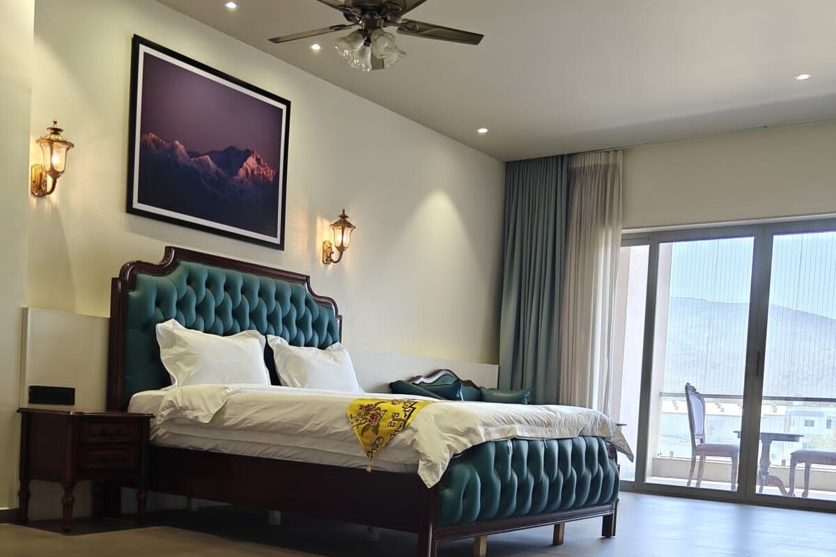 Un dormitorio espacioso con una cama grande, un ventilador de techo, un cuadro enmarcado en la pared y vistas por la ventana.