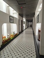 Un pasillo con suelo estampado, cuadros en las paredes y esculturas de animales a la izquierda.