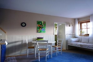 A room with a dining table, chairs, a bed, a wall clock, and a painting. - Holiday apartment with 2 bedrooms (Görisried)