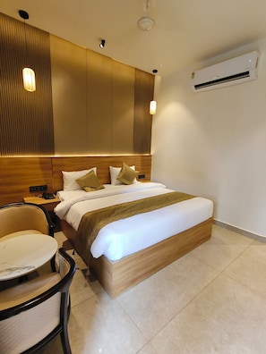 Une chambre d’hôtel équipée d’un lit, d’une table de chevet, d’une chaise et d’un appareil de climatisation.