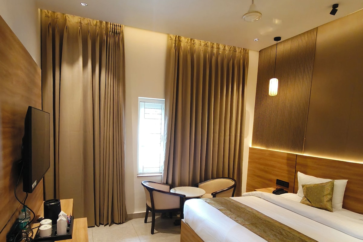 Une chambre d’hôtel avec un lit, un bureau avec une télévision, une chaise et une petite table.