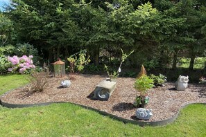 A garden with a variety of plants, a birdhouse, a decorative owl statue, and a small pond. - Holiday apartment with 1 bedroom (Bodenmais)