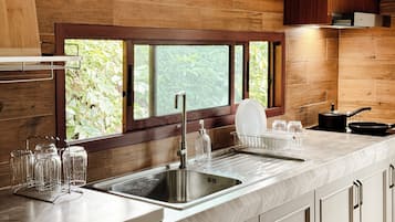 A modern kitchen with a large window, stainless steel sink, and a dish rack.