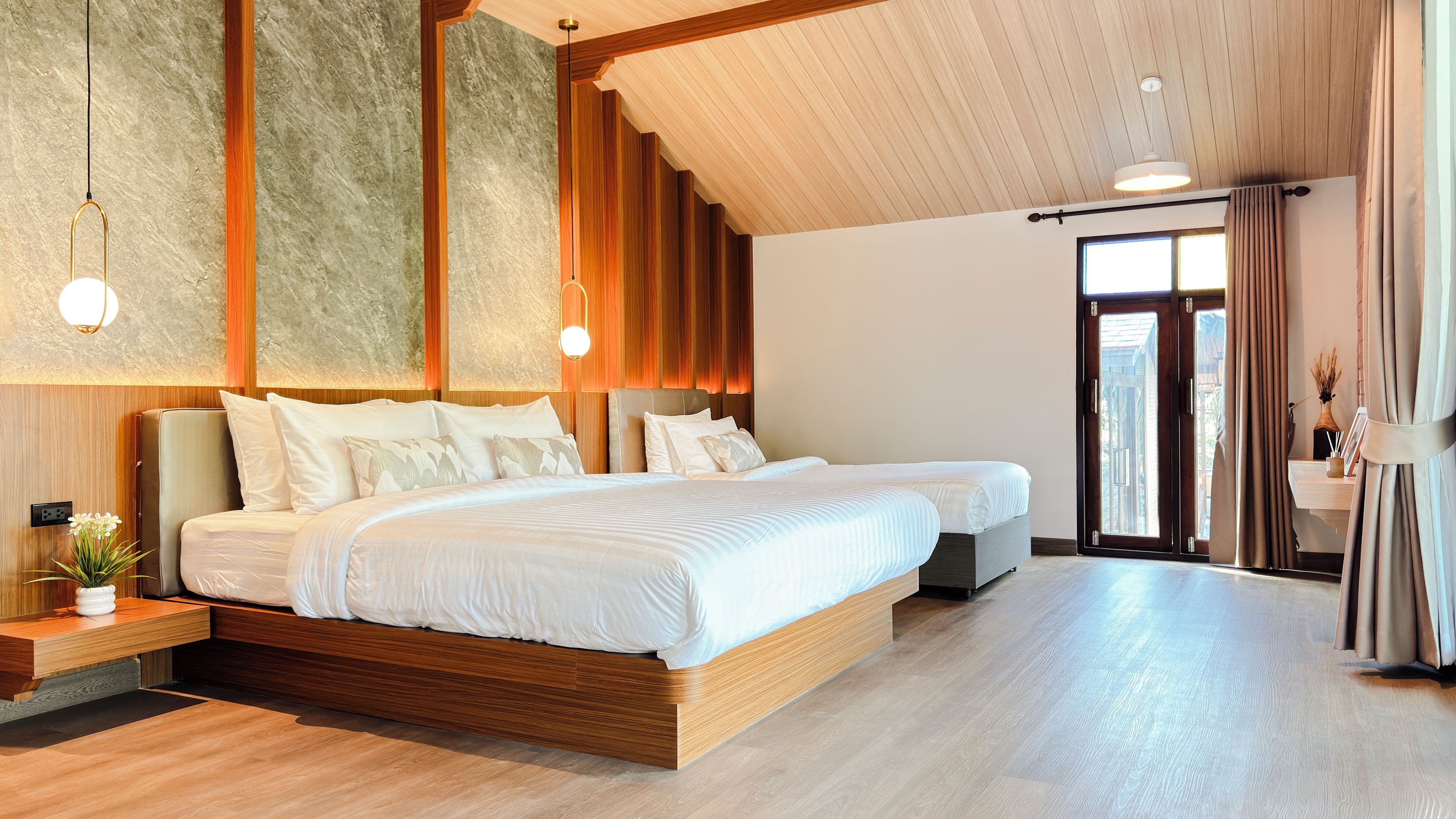Ein geräumiges Schlafzimmer mit einem großen Bett, einem Nachttisch mit einer Vase und Blick ins Freie durch eine Tür.