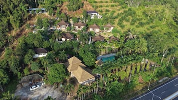 An aerial view of a residential area with multiple houses, a swimming pool, and lush greenery.