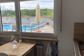 A room with a view of a swimming pool, a table with decorative items, and a window with a view of greenery. - Holiday apartment in Salem with swimming pool (Salem)