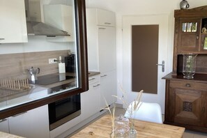 A modern kitchen with white cabinets, a wooden countertop, and a built-in oven. - Holiday apartment in Salem with swimming pool (Salem)
