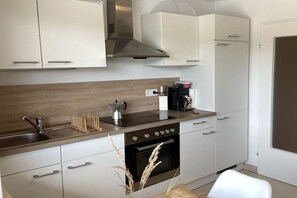 A modern kitchen with white cabinets, a stainless steel oven, and a wooden countertop. - Holiday apartment in Salem with swimming pool (Salem)