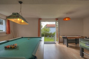 A pool room with a pool table and a billiards table, a window with curtains, and a door leading outside. - Holiday home in Bärnau with swimming pool (Bärnau)
