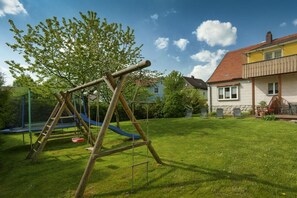 A residential area with a swing set, a slide, and a house with a red roof. - Holiday home in Bärnau with swimming pool (Bärnau)