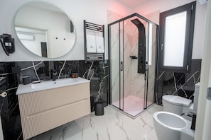 Een moderne badkamer met een douche met glazen wand, een grote spiegel en een wastafelmeubel met een wastafel.