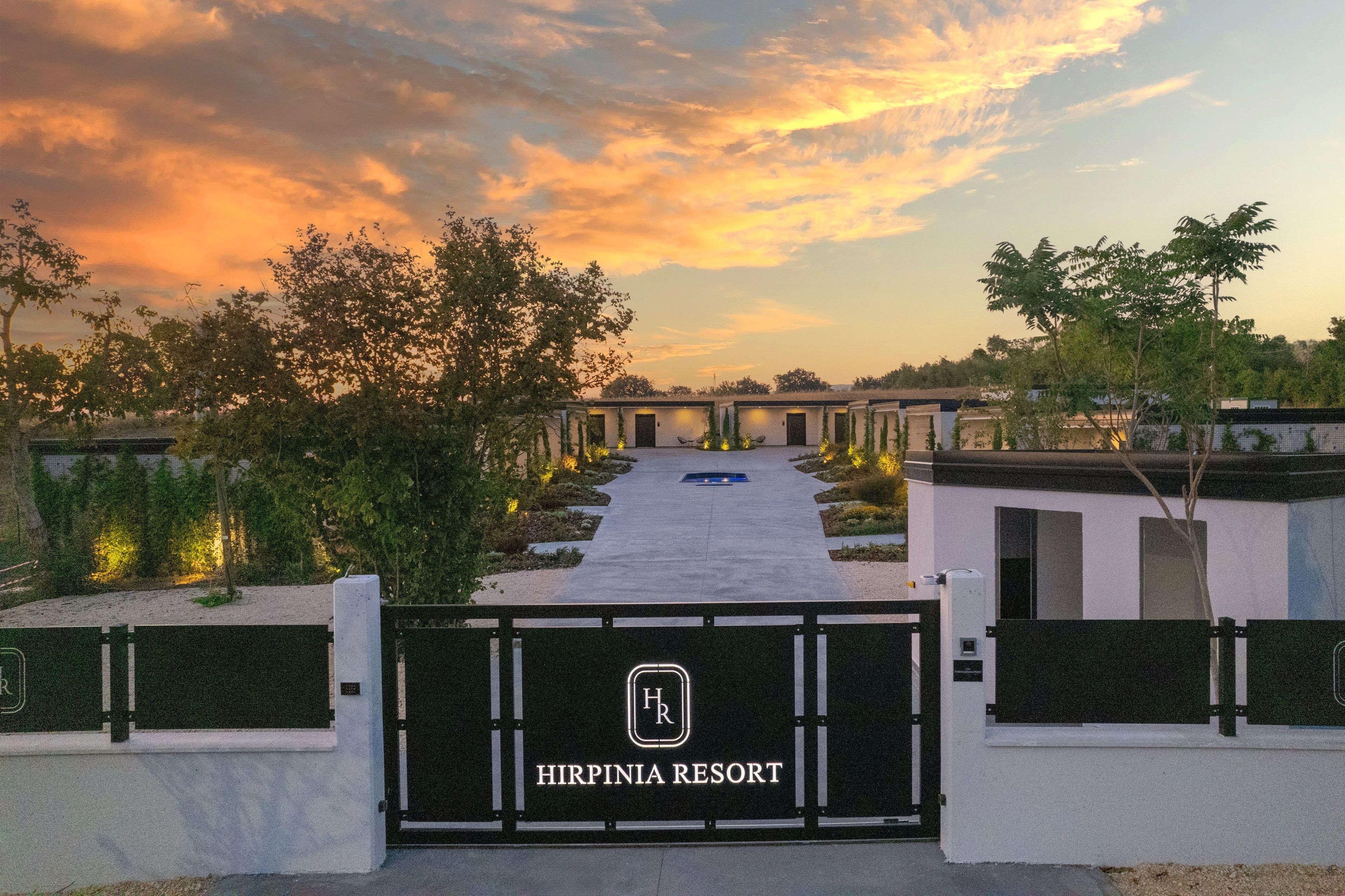 A gated entrance to a resort with a clear pathway leading to multiple buildings.