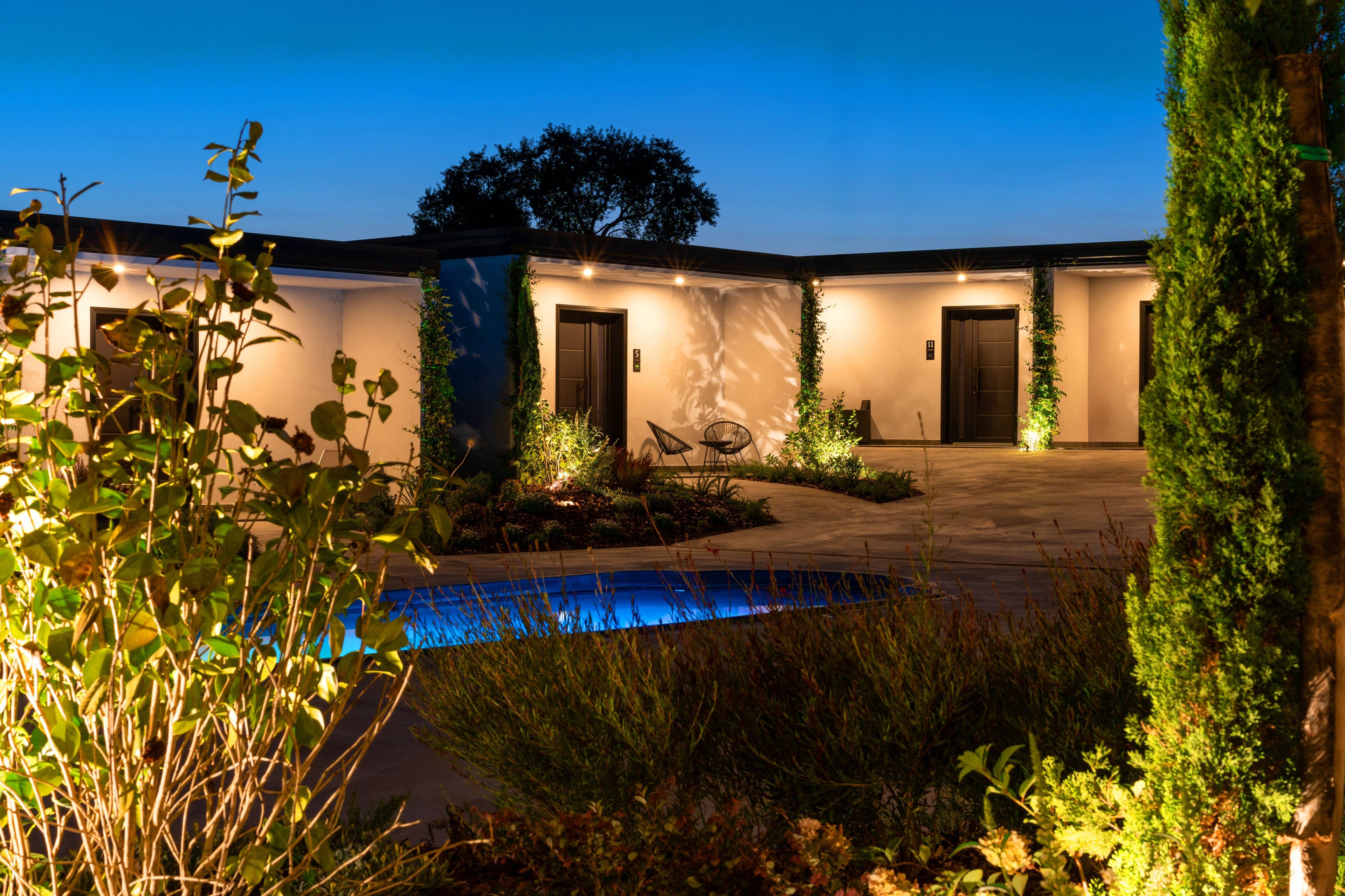 A modern building with a pool, two doors, and a well-lit entrance.