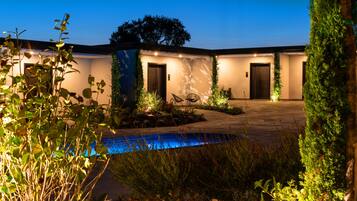 A modern building with a pool, two doors, and a well-lit entrance.