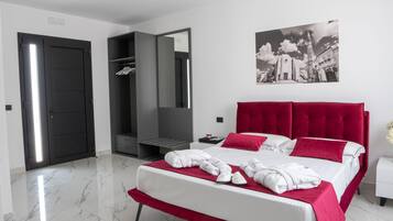 A modern bedroom with a large bed, a wardrobe, a mirror, and a wall-mounted picture.
