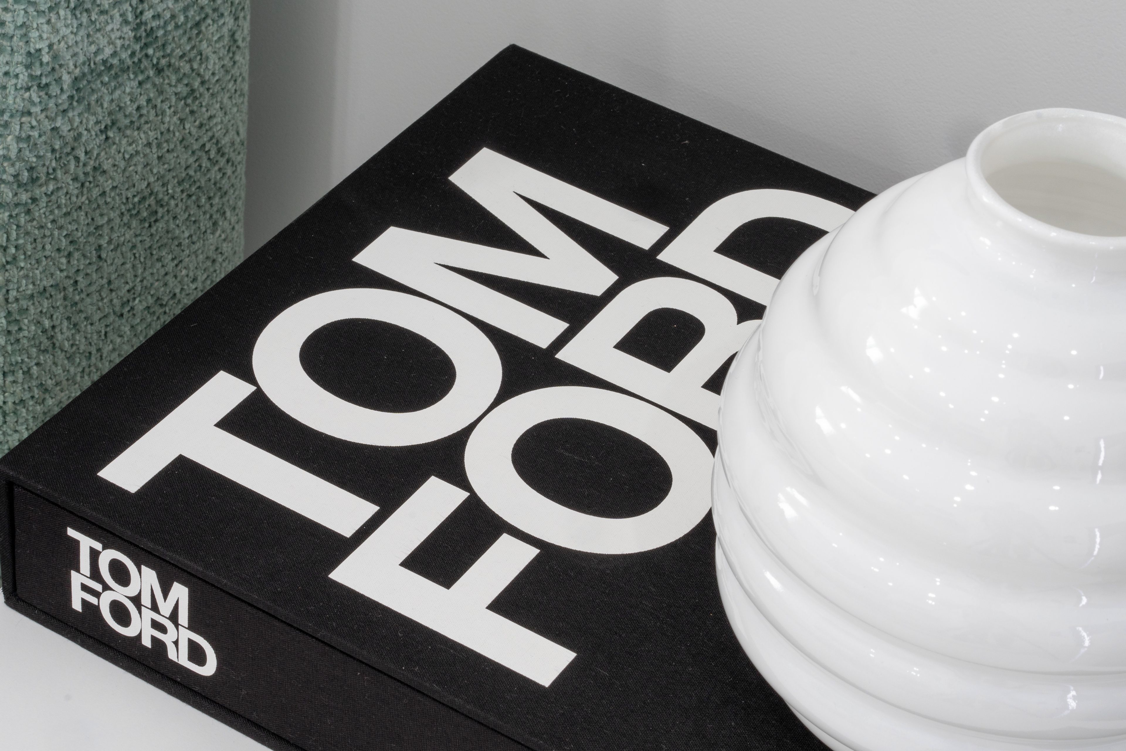 Una caja negra con texto blanco que dice 'TOM FORD' y un jarrón blanco.