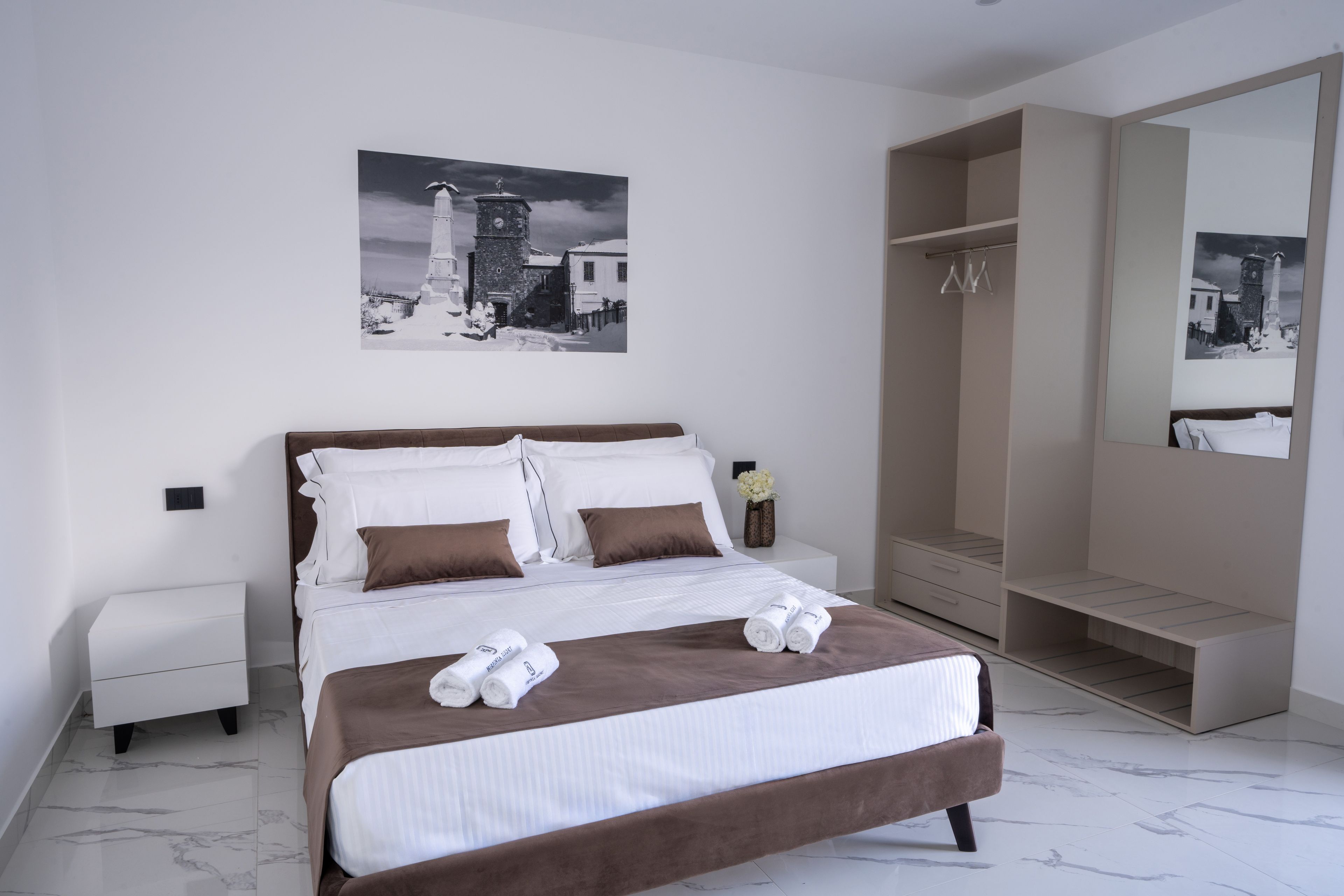 Ein modernes Schlafzimmer mit einem großen Bett, einem Kleiderschrank und einem Spiegel.
