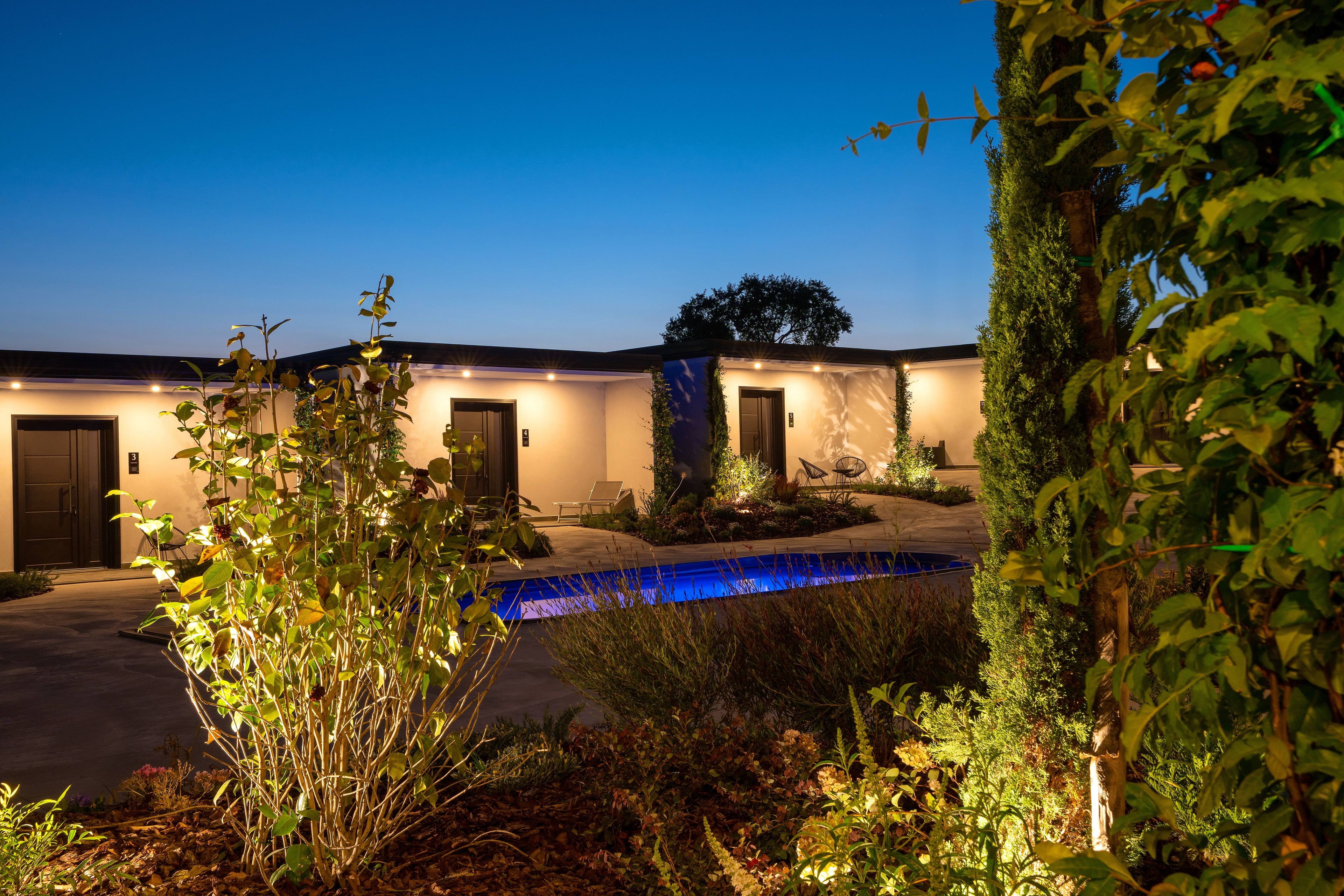 A hotel with a pool, multiple doors, and a well-lit entrance.