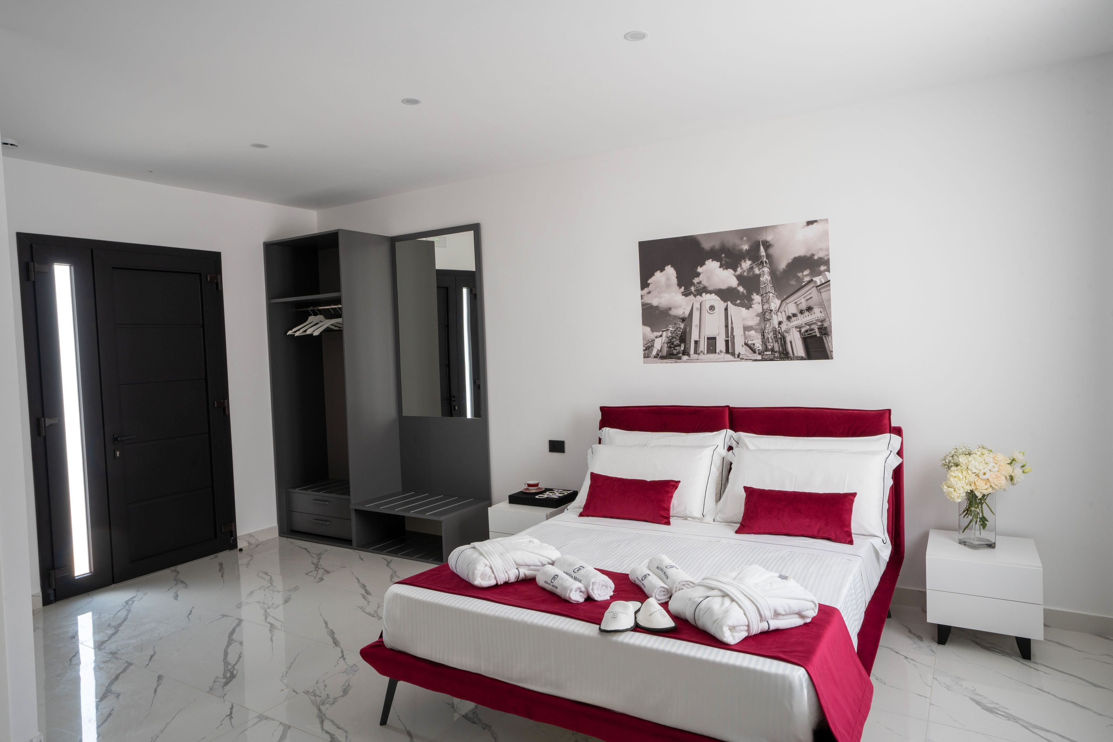 A modern hotel room with a large bed, a wardrobe, a mirror, and a picture on the wall.