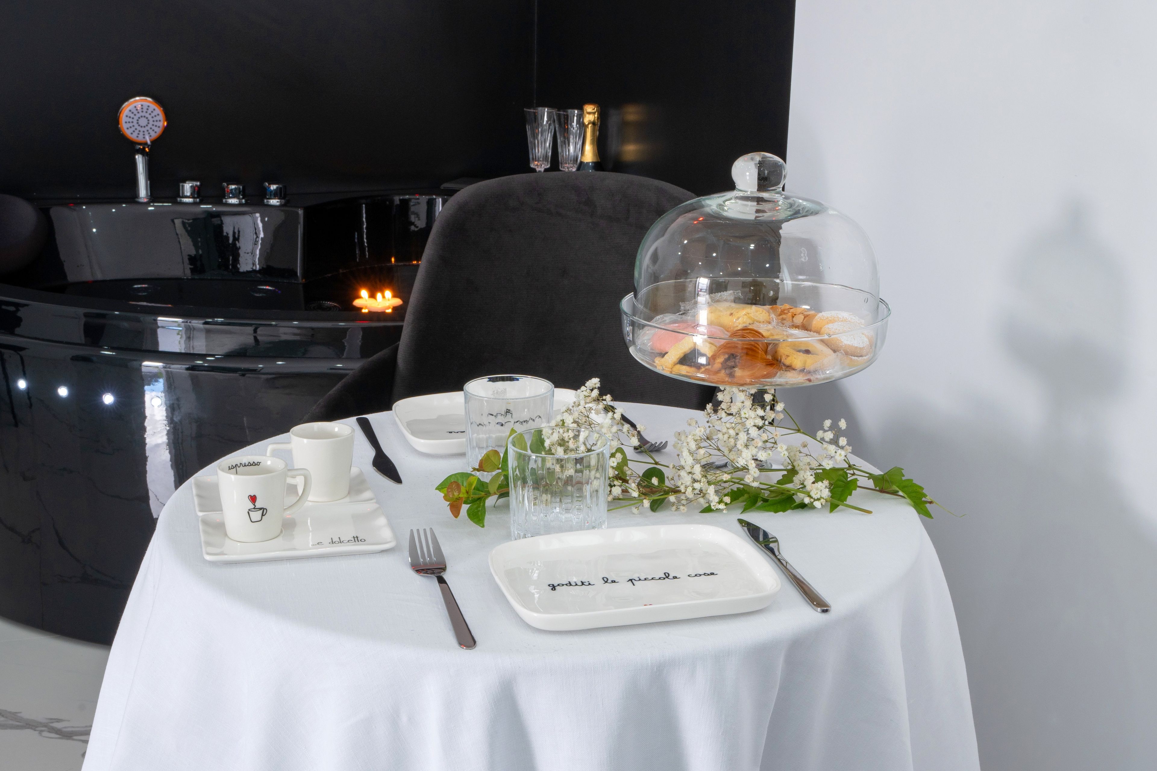 A table set with white tablecloth, plates, cutlery, and a glass bowl with pastries.
