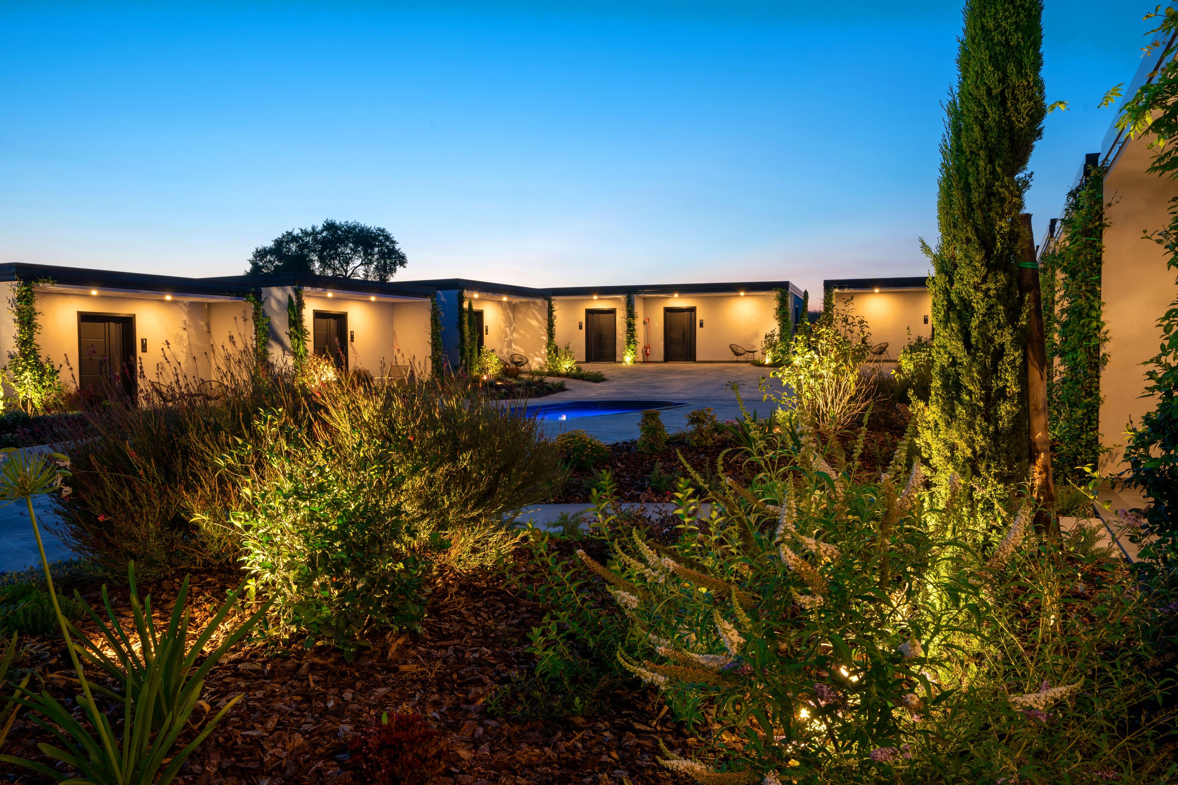 A modern building with multiple doors, a swimming pool, and well-maintained landscaping.