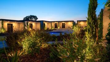 A modern building with multiple doors, a swimming pool, and well-maintained landscaping.