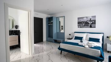 A modern bedroom with a large bed, a walk-in closet, and a bathroom with a marble floor.