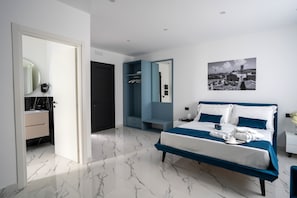 Een moderne slaapkamer met een groot bed, een inloopkast en een badkamer met een marmeren vloer.
