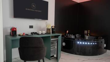 A modern room with a desk, a chair, a flat-screen TV, a minibar, and a decorative vase.