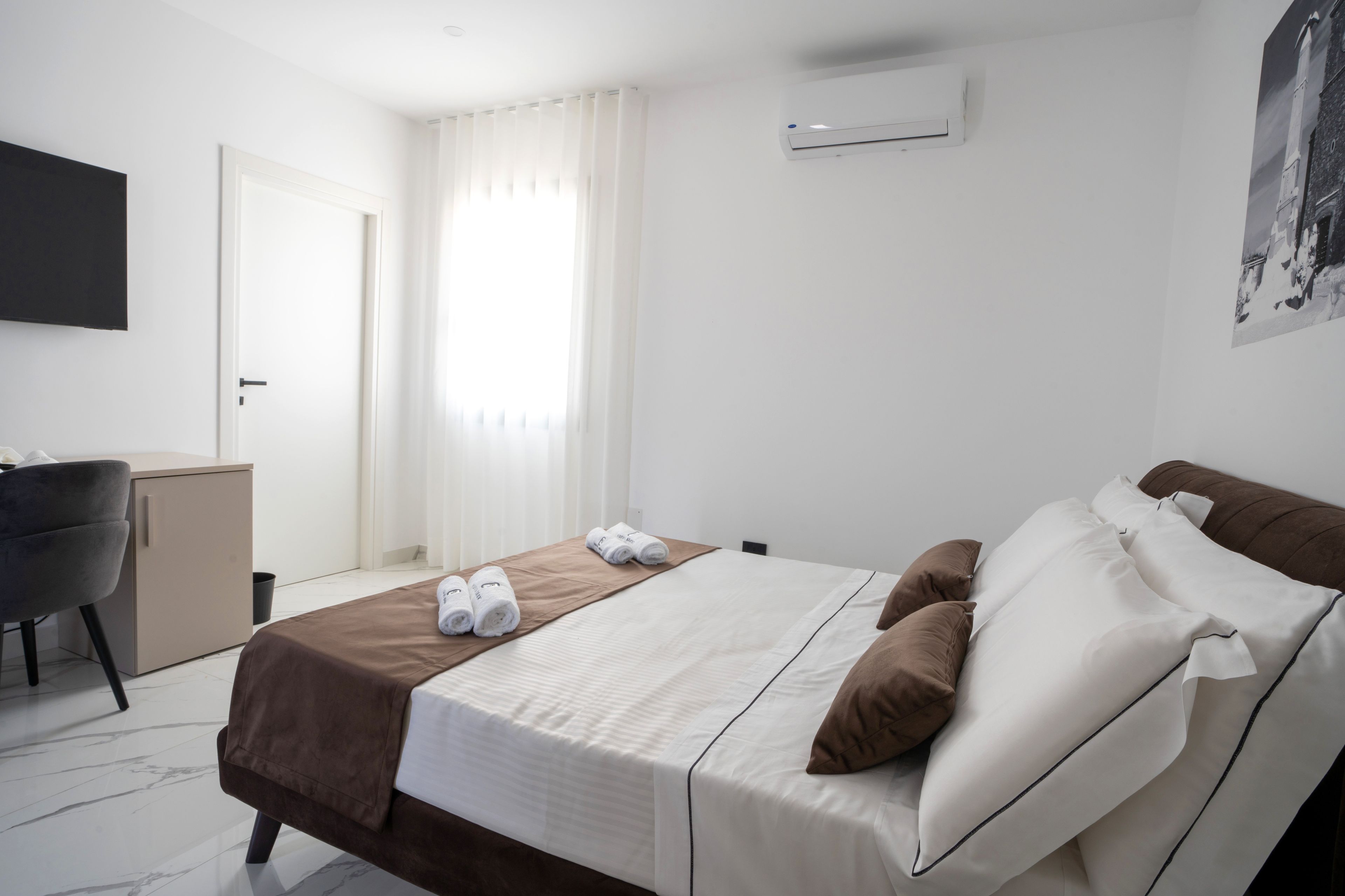 Una camera d'albergo con un letto, una scrivania, una sedia e un condizionatore d'aria.