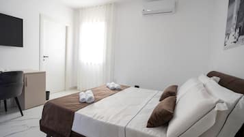 Una camera d'albergo con un letto, una scrivania, una sedia e un condizionatore d'aria.