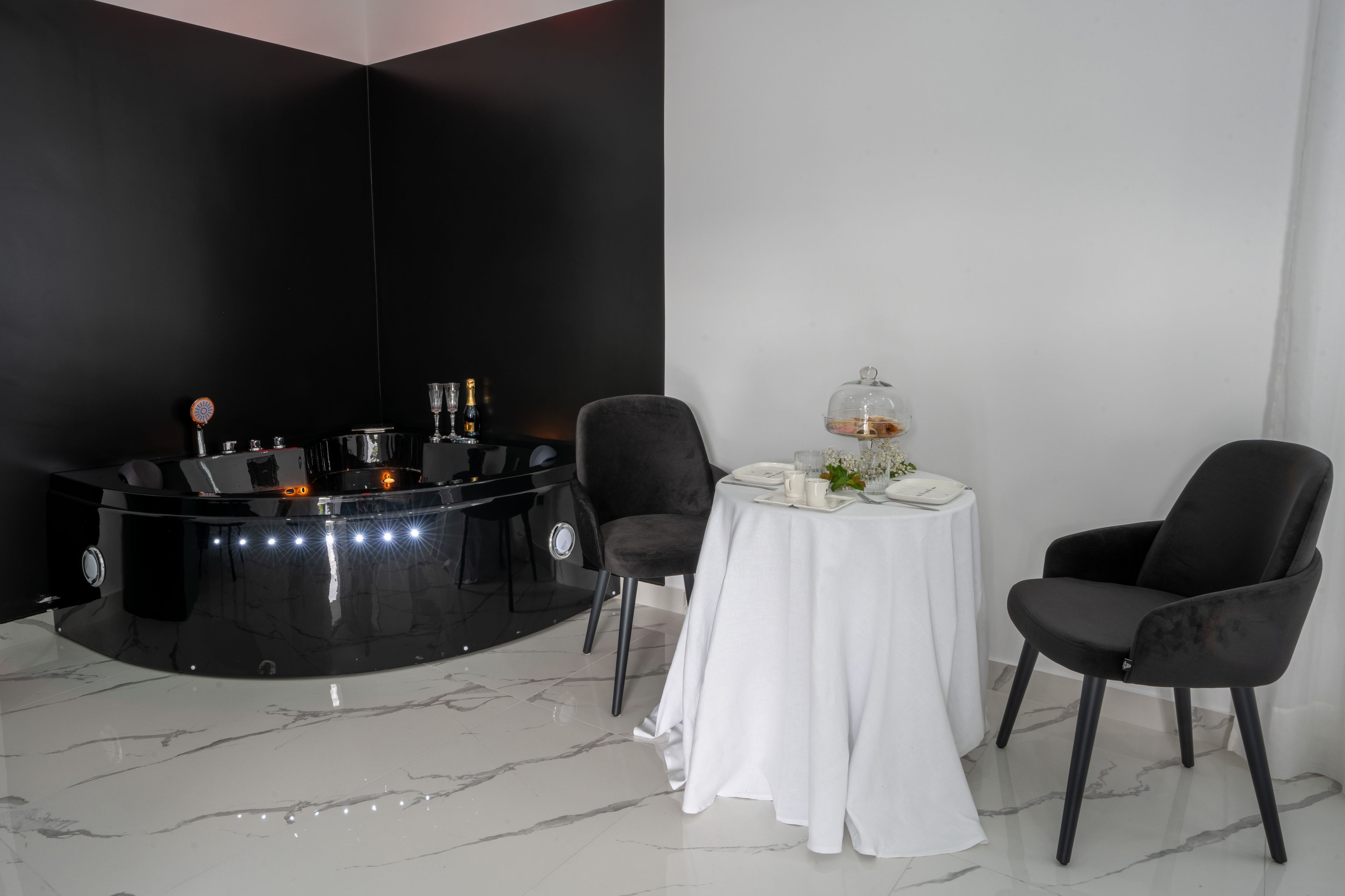 A modern dining area with a black bar, white tablecloth, and black chairs.